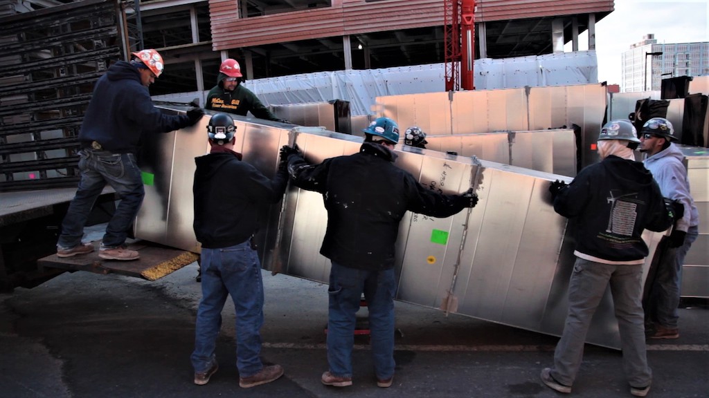 workers unloading ductwork from truck 